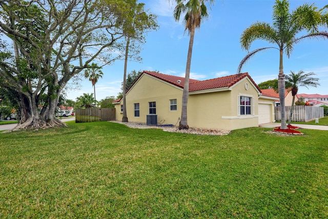 view of side of property featuring a garage, a lawn, and central air condition unit