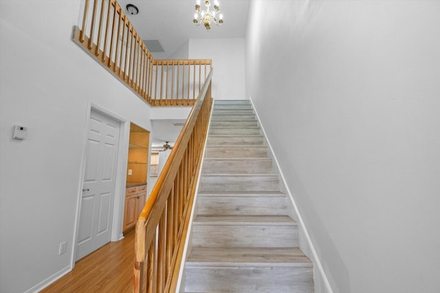 staircase featuring an inviting chandelier and hardwood / wood-style floors