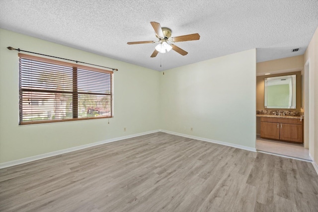 empty room featuring sink, a textured ceiling, light hardwood / wood-style flooring, and ceiling fan