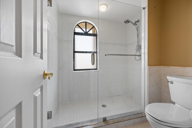 bathroom featuring tile walls, toilet, and walk in shower