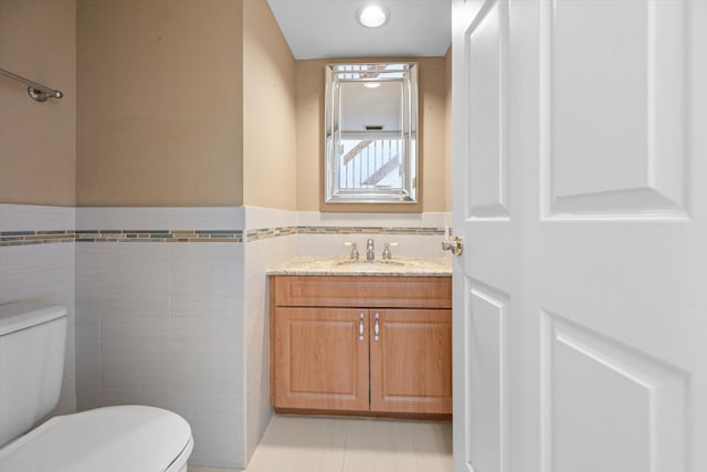 bathroom featuring vanity, toilet, tile patterned flooring, and tile walls