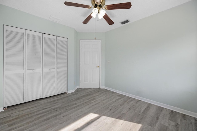 unfurnished bedroom with hardwood / wood-style floors, ceiling fan, and a closet