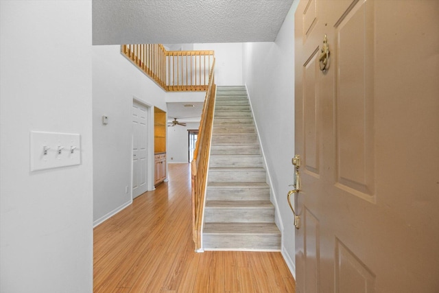 staircase with wood-type flooring and a textured ceiling