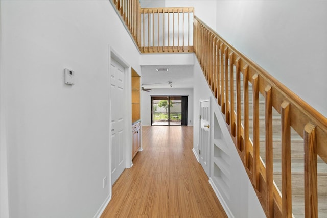 hall featuring light hardwood / wood-style floors and a high ceiling