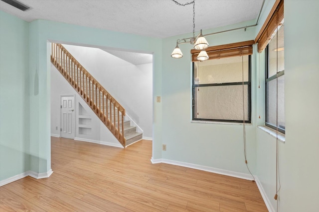 spare room featuring light hardwood / wood-style floors and a textured ceiling