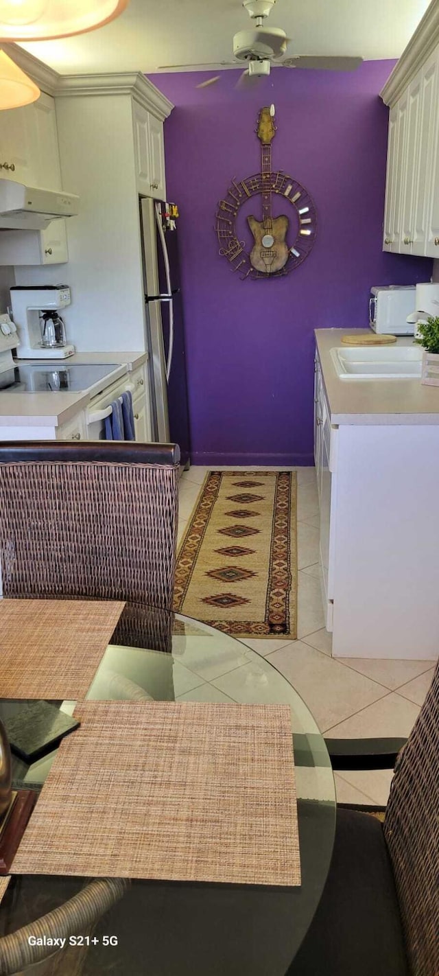 interior space with sink, light tile patterned floors, stainless steel refrigerator, dishwasher, and ceiling fan