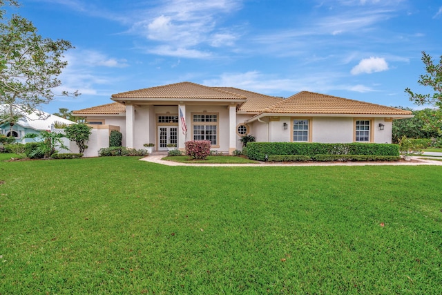 mediterranean / spanish-style house with a front lawn and french doors