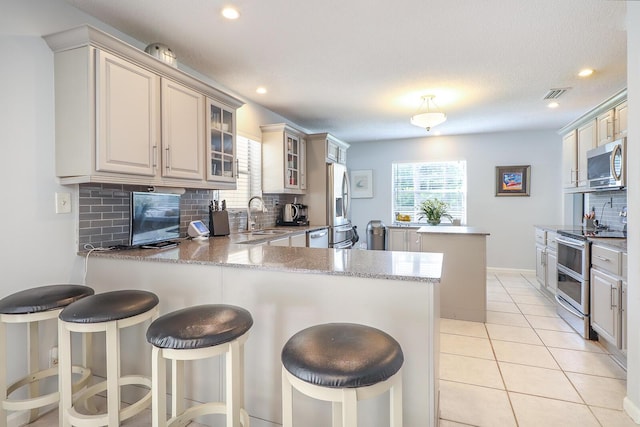 kitchen with stainless steel appliances, kitchen peninsula, and decorative backsplash