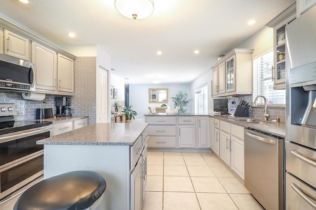 kitchen with appliances with stainless steel finishes, sink, backsplash, a center island, and kitchen peninsula