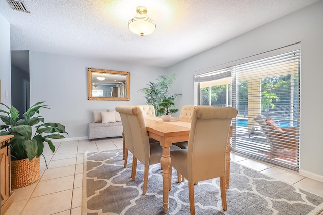 tiled dining room featuring a textured ceiling