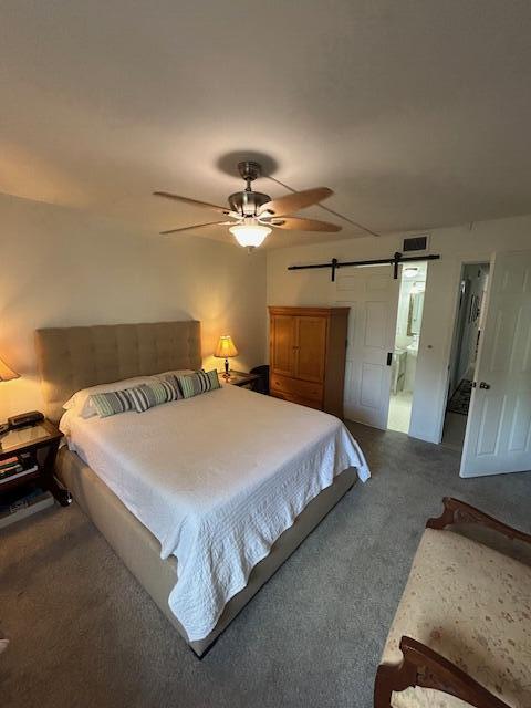 bedroom featuring ceiling fan, carpet flooring, connected bathroom, and a barn door