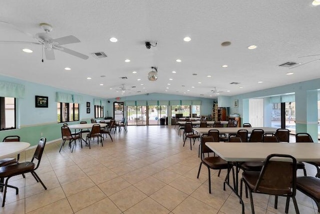 tiled dining room with lofted ceiling, ceiling fan, and a textured ceiling