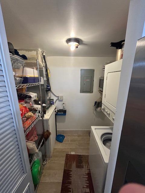 laundry room with stacked washer and dryer, electric panel, and light hardwood / wood-style flooring