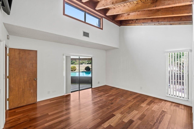 unfurnished room featuring beamed ceiling, baseboards, visible vents, and wood finished floors