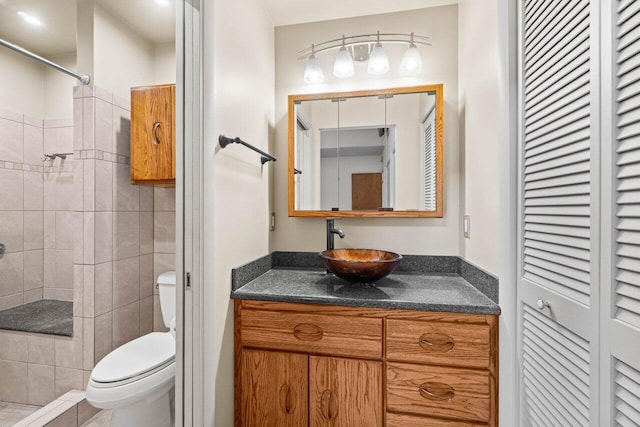 full bath with vanity, toilet, a closet, and a tile shower