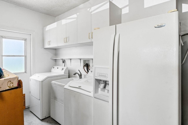 clothes washing area with washer and dryer, cabinet space, and a textured ceiling