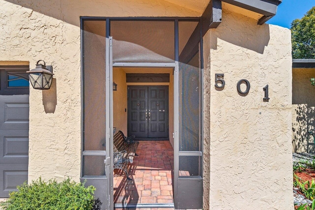 view of exterior entry with a garage and stucco siding