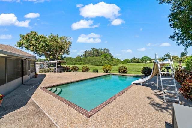 pool featuring a yard, a patio area, and a water slide