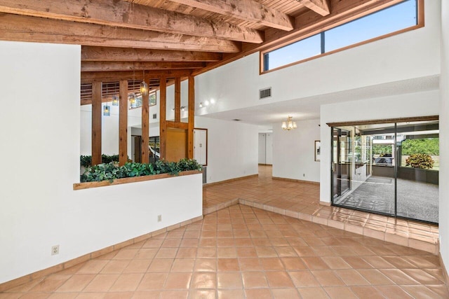 unfurnished room featuring tile patterned floors, beamed ceiling, visible vents, and a wealth of natural light