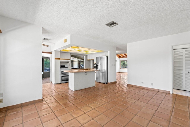 kitchen with visible vents, a healthy amount of sunlight, white cabinets, and stainless steel fridge with ice dispenser