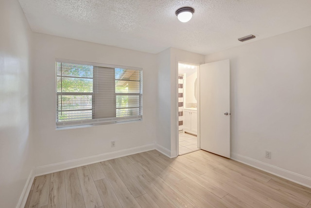 spare room with light hardwood / wood-style floors and a textured ceiling