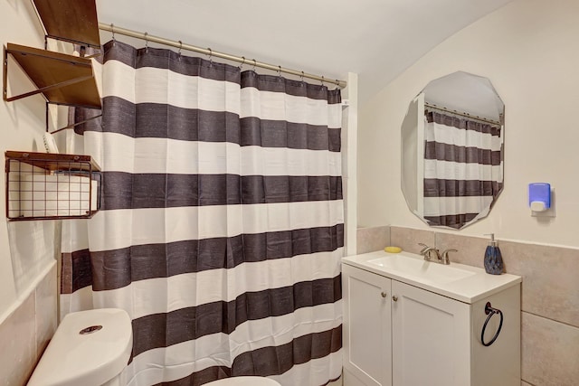 bathroom with tile walls, vanity, and toilet