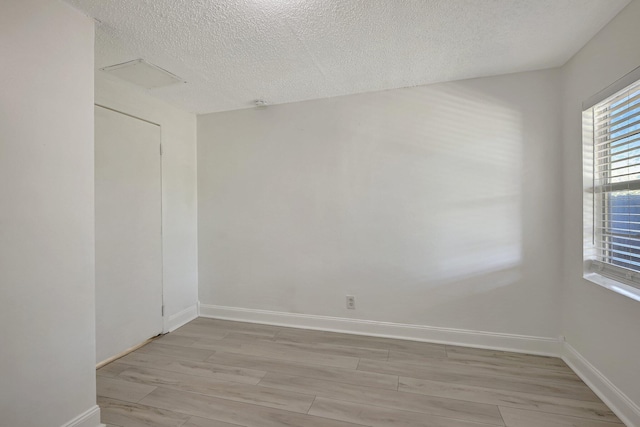 empty room with a textured ceiling and light hardwood / wood-style flooring