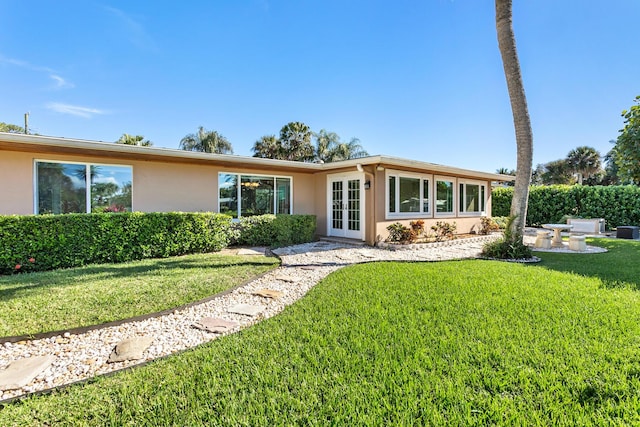 single story home with a front lawn and french doors