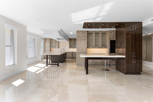 kitchen with a large island, light countertops, decorative backsplash, a sink, and a kitchen breakfast bar