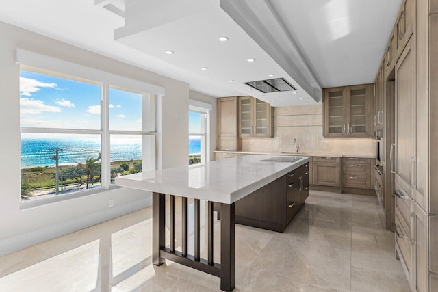 kitchen featuring a spacious island, glass insert cabinets, light stone countertops, black electric cooktop, and backsplash