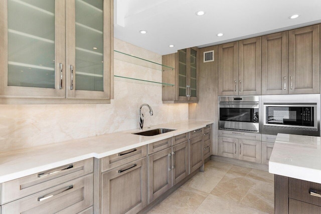 kitchen featuring light countertops, a sink, oven, and built in microwave