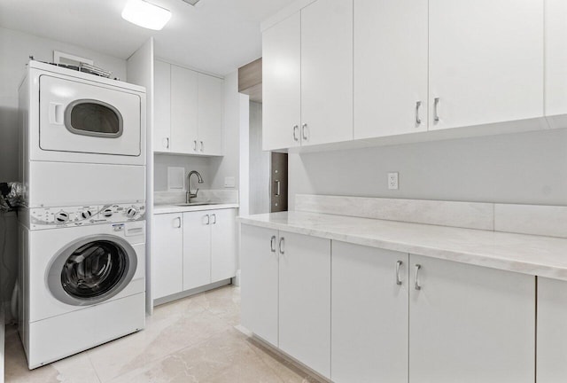 clothes washing area featuring stacked washer / drying machine, cabinet space, and a sink