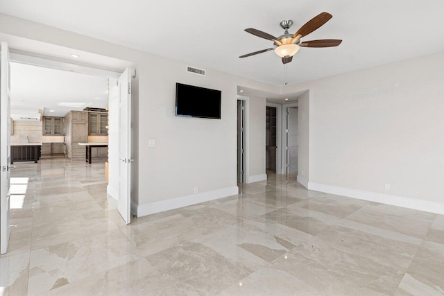 unfurnished room featuring marble finish floor, ceiling fan, and baseboards