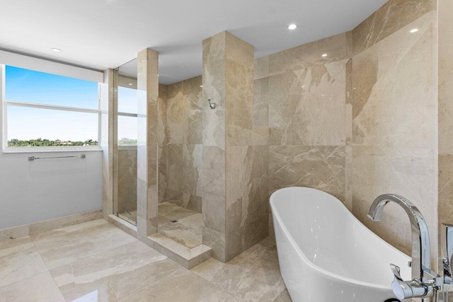 bathroom with a soaking tub, tiled shower, and tile walls