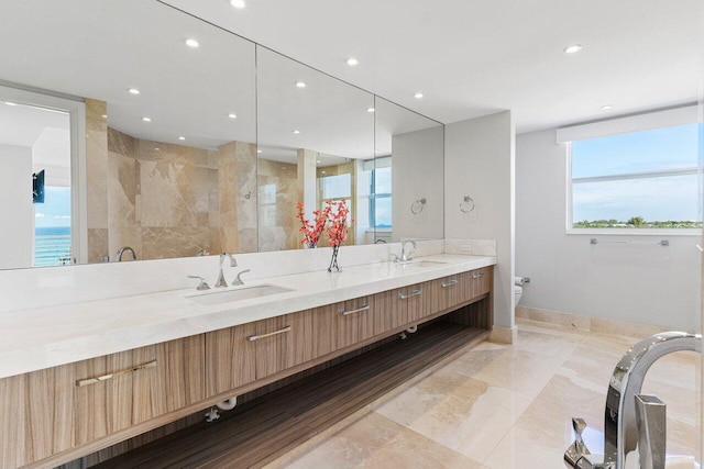 full bath with double vanity, toilet, a sink, and recessed lighting