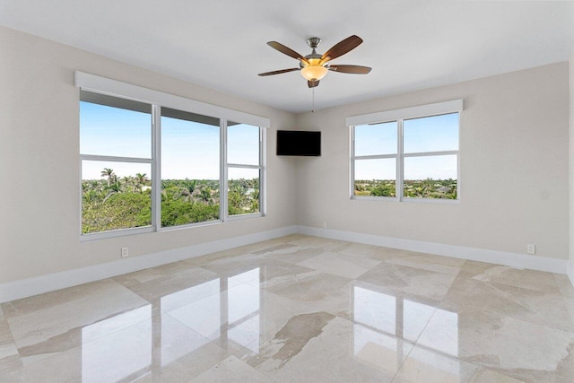 unfurnished room with marble finish floor, a ceiling fan, and baseboards