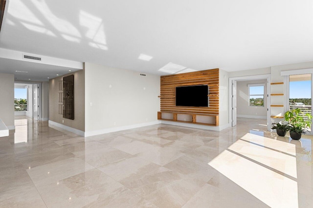 unfurnished living room with baseboards, visible vents, and a healthy amount of sunlight