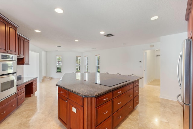 kitchen featuring dark stone countertops, stainless steel appliances, and a center island