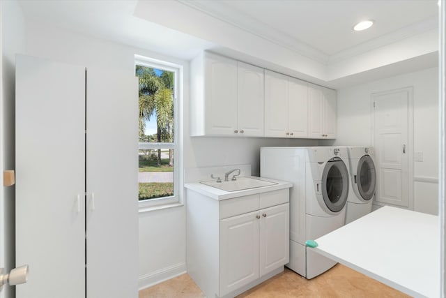 clothes washing area featuring crown molding, cabinets, sink, and washing machine and dryer