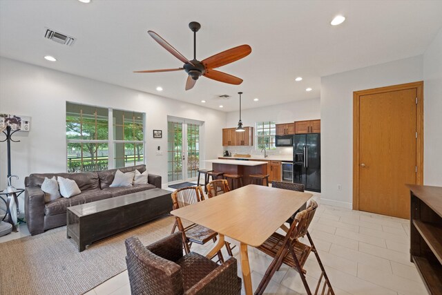 tiled dining space featuring sink, ceiling fan, and french doors