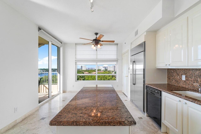 kitchen featuring dishwasher, dark stone countertops, backsplash, white cabinetry, and stainless steel built in fridge