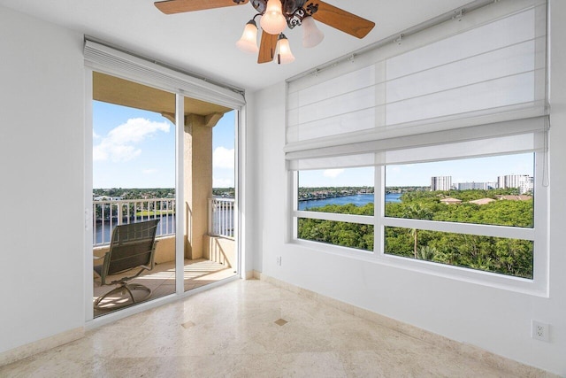 unfurnished room with ceiling fan, a healthy amount of sunlight, and a water view