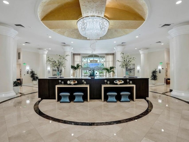 reception area featuring decorative columns and an inviting chandelier