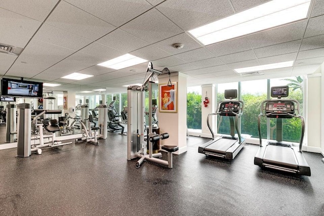 workout area featuring a drop ceiling and a wall of windows