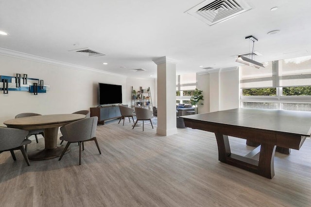 game room featuring hardwood / wood-style flooring, ornamental molding, and decorative columns