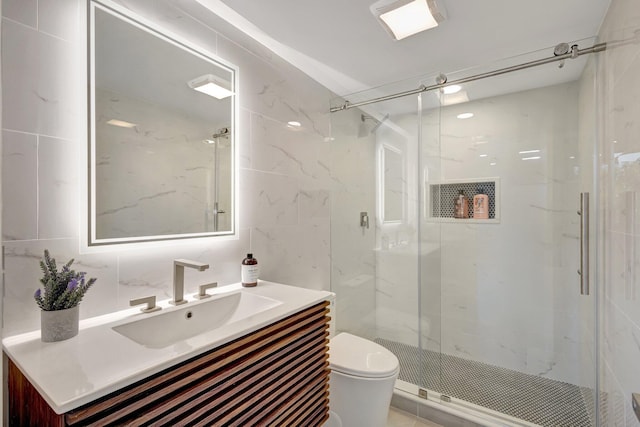 bathroom with tile walls, vanity, toilet, and walk in shower