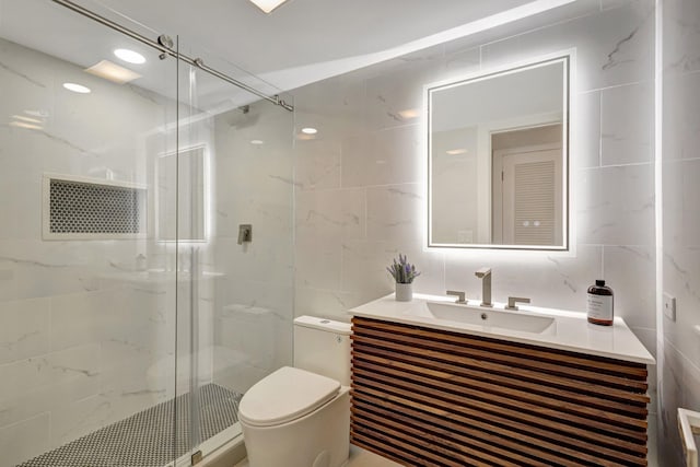 bathroom with tile walls, an enclosed shower, vanity, and toilet