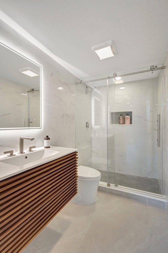 bathroom featuring a shower with door, vanity, tile walls, and toilet