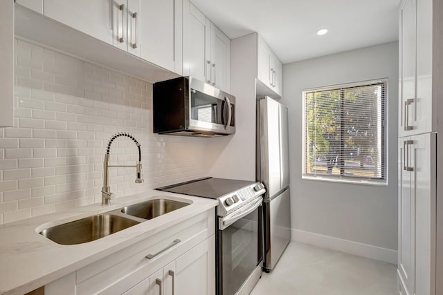 kitchen with sink, white cabinetry, backsplash, stainless steel appliances, and light stone counters