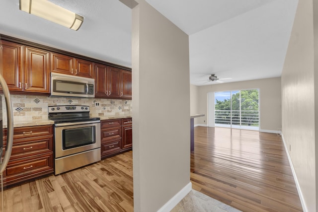 kitchen with tasteful backsplash, stainless steel appliances, light stone counters, and light wood-type flooring